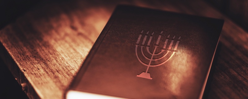 Leather-bound Torah book with menorah on the cover.